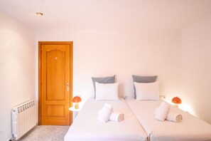 A hotel room with a wooden door, two beds with white linens, two pillows, two bedside lamps, and a radiator. - Majordoms Ponent, Banyoles (Banyoles)