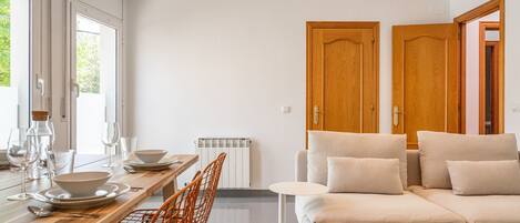 Un intérieur moderne comprenant un coin repas, un canapé et deux portes en bois.