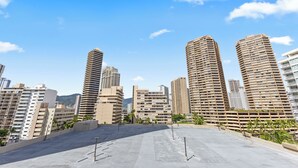 A rooftop with a view of high-rise buildings, including a distinctive cylindrical structure and several rectangular buildings with balconies. - Ilikai Marina - Modern Designer Studio (Honolulu)