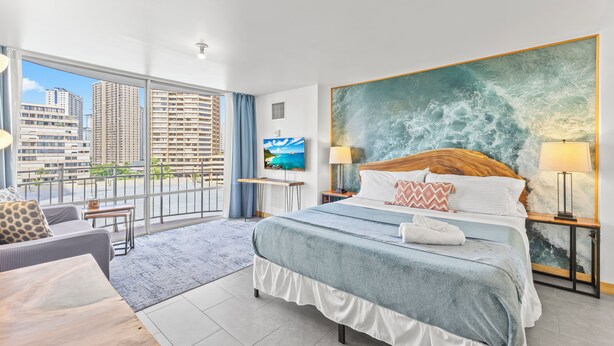 A hotel room with a bed, a large window, a city view, and a painting on the wall. - Ilikai Marina - Modern Designer Studio (Honolulu)
