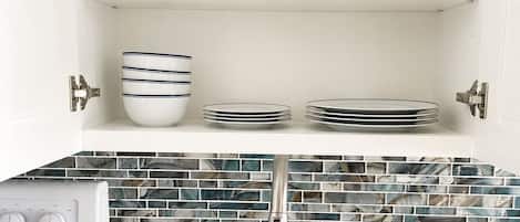 A kitchen with a built-in stove, a sink, and a backsplash with blue and white tiles.