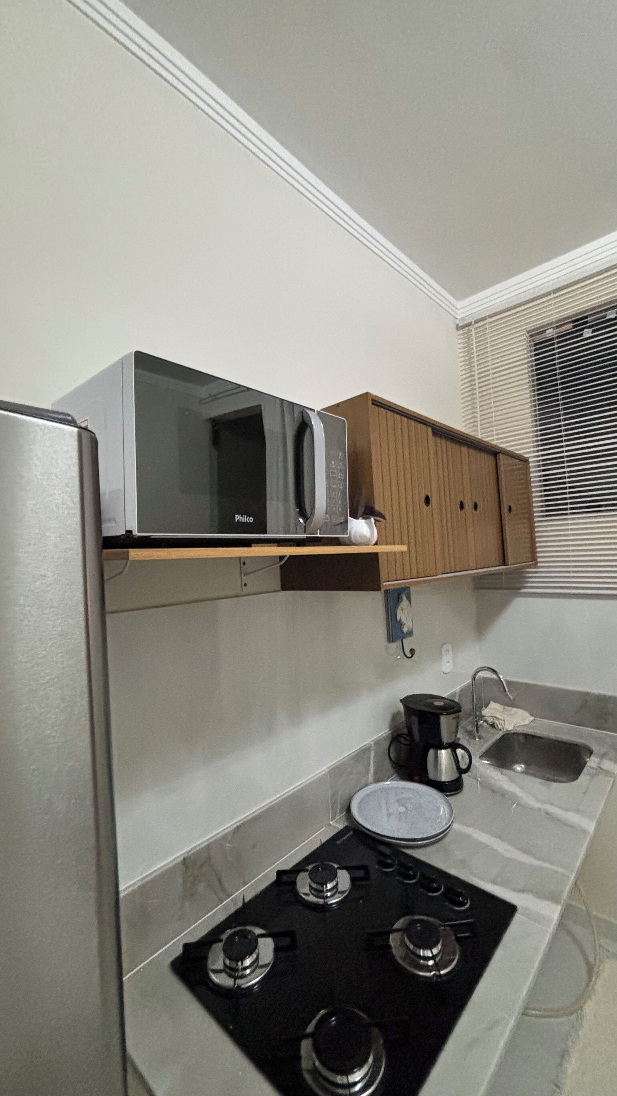 A compact kitchen with a microwave, a coffee maker, and a gas stove.