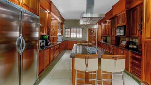 Una cocina con armarios de madera, electrodomésticos de acero inoxidable y una isla central con sillas.