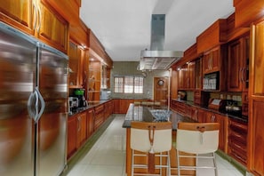 Una cocina con armarios de madera, electrodomésticos de acero inoxidable y una isla central con sillas.