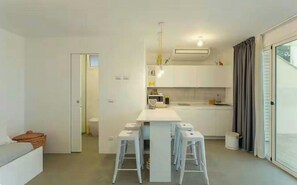 A modern kitchen with white cabinets, a central island with stools, and a view to the outside. - Studio between Cefalù and the Madonie (Cefalù)
