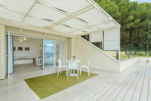 A modern outdoor patio with a covered seating area, a dining table, and a staircase leading to an upper level. - Studio between Cefalù and the Madonie (Cefalù)