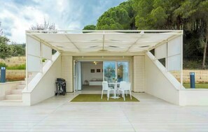A modern outdoor patio with a covered seating area, a table, and chairs. - Studio between Cefalù and the Madonie (Cefalù)