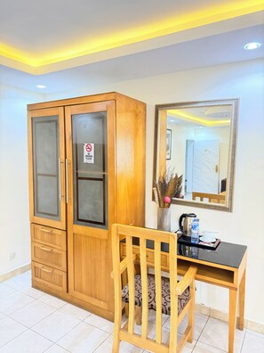 A room with a wooden wardrobe, a desk with a chair, a mirror, and a sign prohibiting smoking. - Floyd Msquare Hotel (Lagos)
