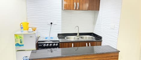A compact kitchen with a gas stove, double sink, and wooden cabinetry.