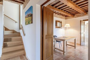 A staircase leading to a room with a wooden door, a table with a chair, and a lamp. - Antica Dimora delle Tre Coste (Marche)