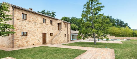 Un edificio de ladrillo con un patio, una piscina y un árbol.