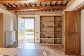 A hallway with a wooden door, a white radiator, and a shelf with books and a vase. - Antica Dimora delle Tre Coste (Marche)