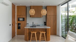 Una cucina moderna con mobili in legno, un'isola centrale con sgabelli, illuminazione a sospensione e vista sul verde.