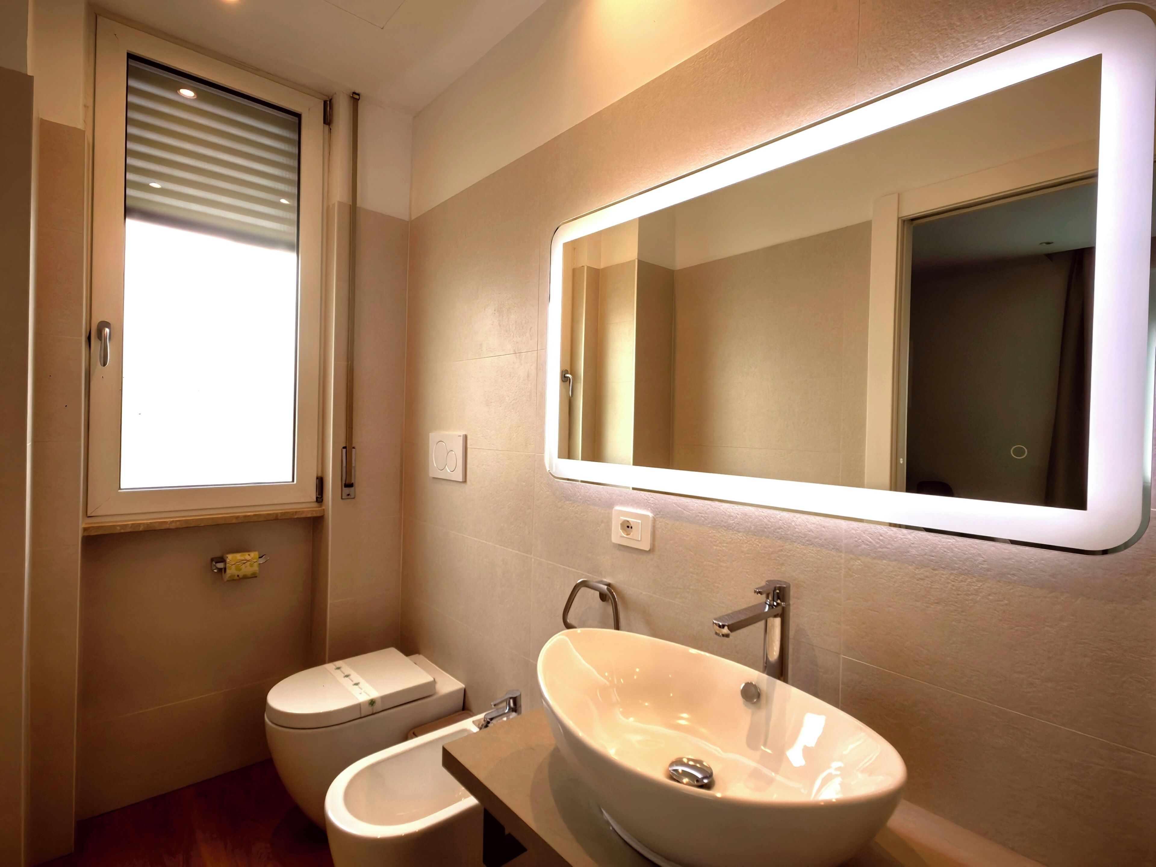 A bathroom with a toilet, bidet, and a large mirror.