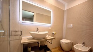 Un baño moderno con un espejo grande, un lavamanos sobre encimera, un inodoro y un bidé.