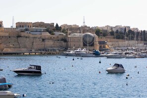 A marina with boats docked, a large spherical structure on a hill, and buildings in the background. - St Angelo Mansions 3BDR flat with Seaview (Birgu)
