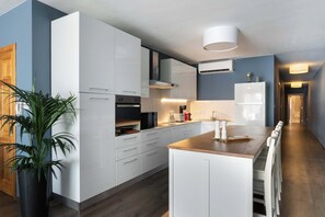 A modern kitchen with white cabinetry, a wooden countertop, and an air conditioning unit on the wall. - St Angelo Mansions 3BDR flat with Seaview (Birgu)