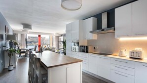 Eine moderne Küche mit weißen Schränken, einer zentralen Kochinsel und Meerblick durch große Fenster.