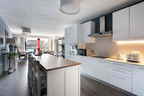 A modern kitchen with white cabinetry, a central island, and a view of the sea through large windows. - St Angelo Mansions 3BDR flat with Seaview (Birgu)