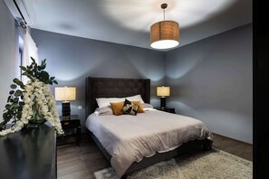 A bedroom with a large bed, two bedside lamps, a hanging light fixture, and a decorative plant. - St Angelo Mansions 3BDR flat with Seaview (Birgu)
