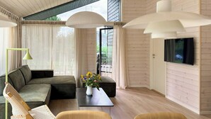 Ein modernes Wohnzimmer mit Sofa, Couchtisch und an der Wand montiertem Fernseher.