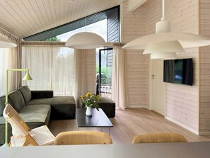 Ein modernes Wohnzimmer mit Sofa, Couchtisch und an der Wand montiertem Fernseher.