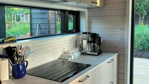 Eine moderne Küche mit Einbauherd, einer Kaffeemaschine und einem Fenster mit Blick auf einen Garten.