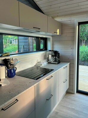 Eine moderne Küche mit Einbauherd, einer Kaffeemaschine und einem Fenster mit Blick auf einen Garten.