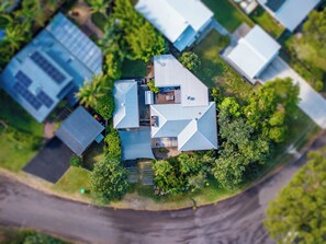 An aerial view of a residential area with multiple houses, each with a distinct roof design and surrounded by greenery. - Coastal Nostalgia – Classic charm, Coastal comfort (Macmasters Beach)