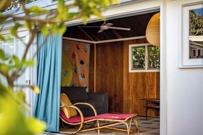 Una habitación con ventilador de techo, un sofá, una silla y una ventana.