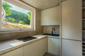 A modern kitchen with a built-in stove, a sink, and a window overlooking a natural landscape. - Villa with infinity pool over the Tyrrhenian Sea (Cefalù)