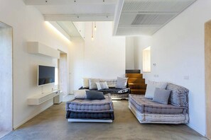 A modern living room with a flat-screen TV, two sofas, and a staircase leading to an upper level. - Villa with infinity pool over the Tyrrhenian Sea (Cefalù)