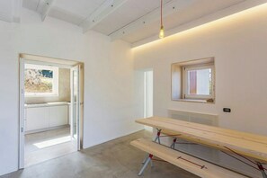 A minimalist room with a large table, a window, and a door leading to an outdoor area. - Villa with infinity pool over the Tyrrhenian Sea (Cefalù)