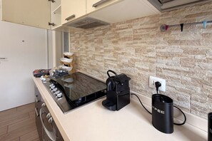 A kitchen with a stove, a coffee machine, and a power outlet on the counter. - Spacious 89 m² apartment, ideal for 6 people, located on the ground floor of a period building with a private entrance (accessible via stairs).Situated in the heart of the historic center, the property offers a splendid view of Rocca Brancaleone Park an (Ravenna)
