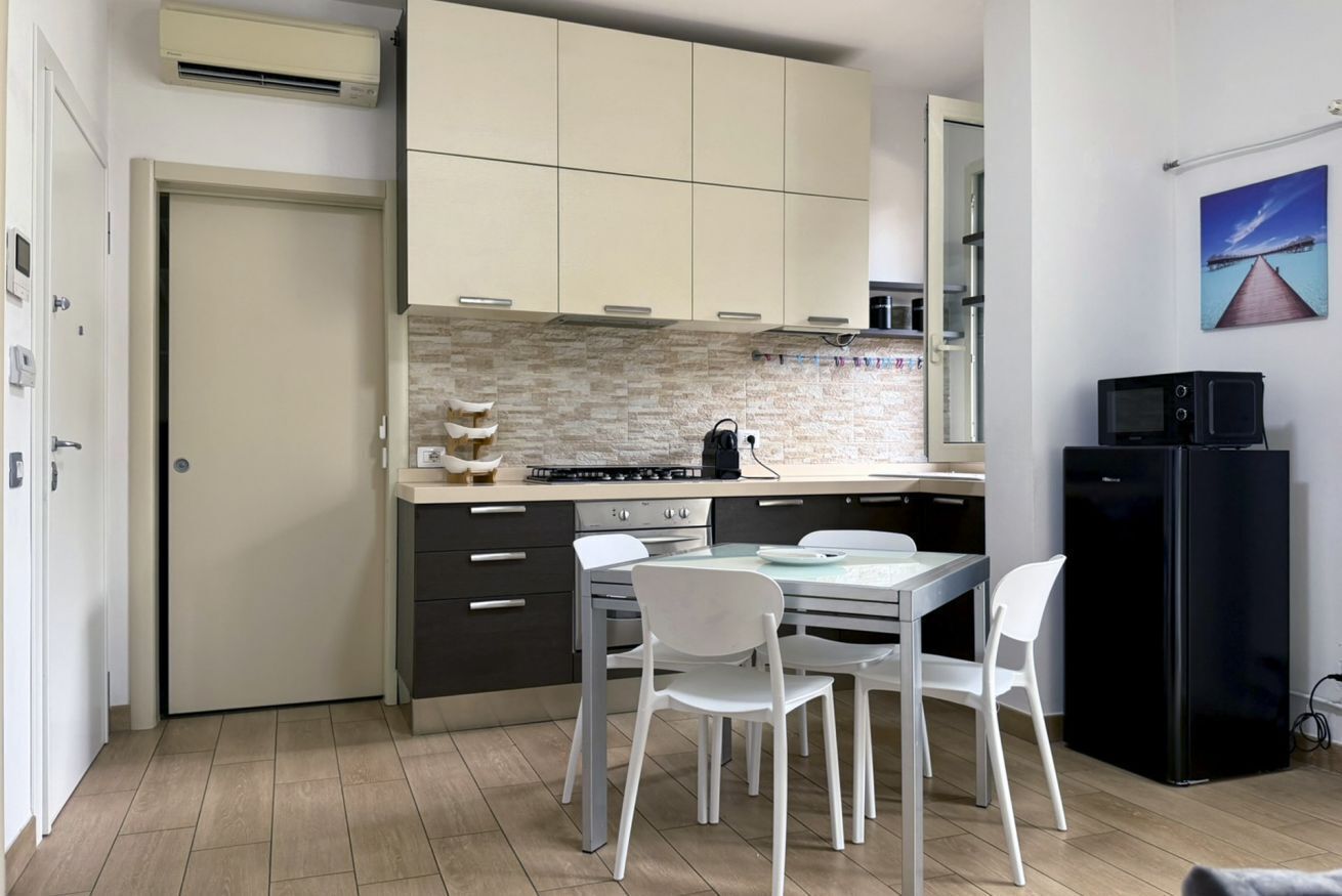 Una cucina compatta con zona pranzo, frigorifero e forno a microonde.