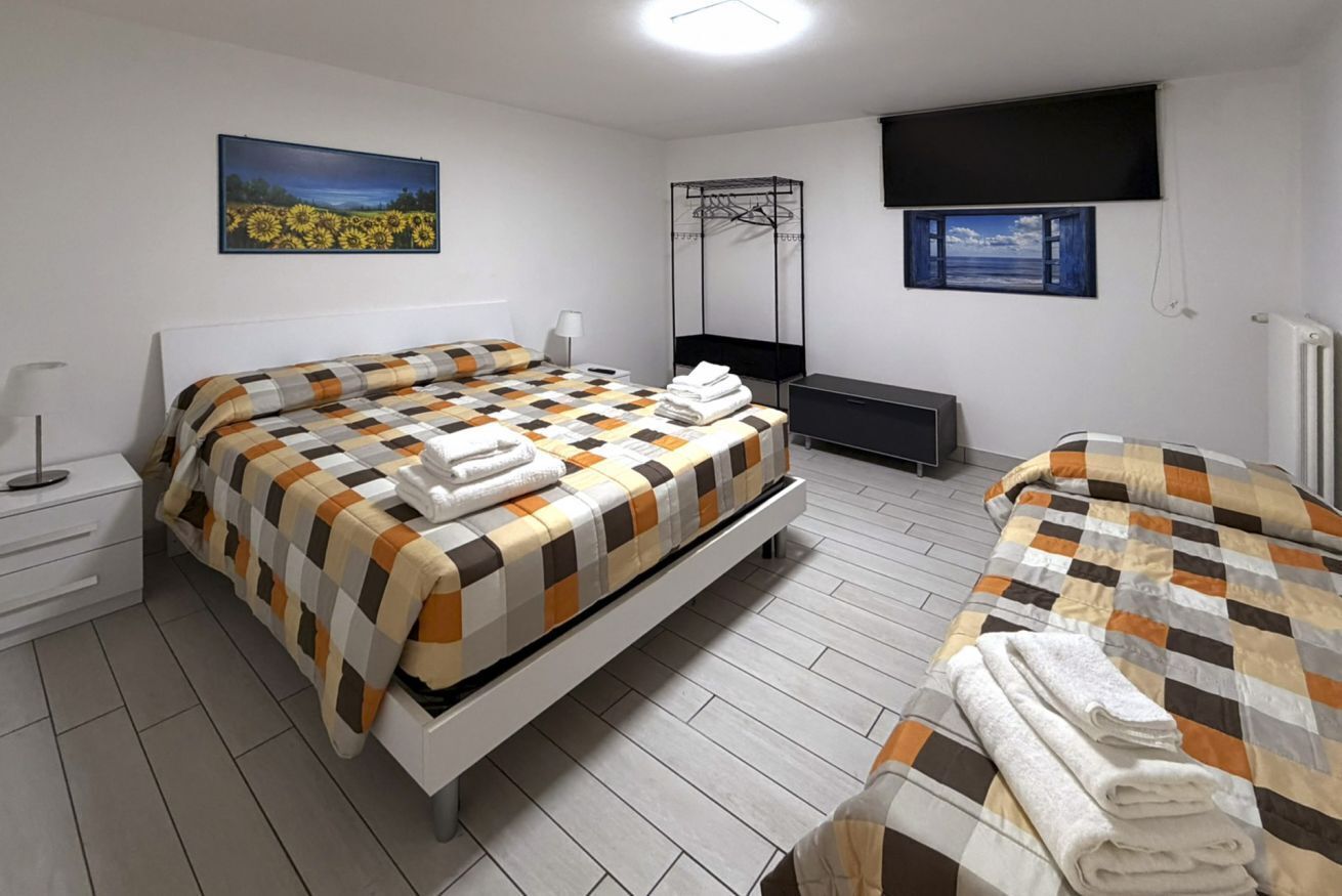 Une chambre à coucher comprenant un lit, une table de chevet, une armoire, un portant à vêtements et un téléviseur.