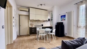 Ein kompakter Wohnbereich mit Küchenzeile, Essbereich und einer Sitzecke mit Sofa.