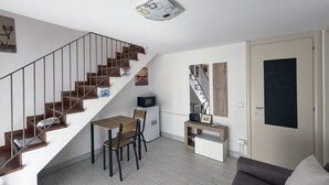 Ein zeitgemäßer Wohnraum mit Treppe, Essbereich, Sofa und einer Tür mit Tafelfläche.