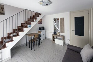 A modern living space with a staircase, a dining area, a sofa, and a door with a chalkboard. - Spacious 89 m² apartment, ideal for 6 people, located on the ground floor of a period building with a private entrance (accessible via stairs).Situated in the heart of the historic center, the property offers a splendid view of Rocca Brancaleone Park an (Ravenna)