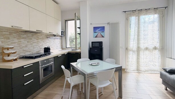 Eine moderne Küche mit Essbereich, einem Kühlschrank und einem Fenster mit Vorhängen.