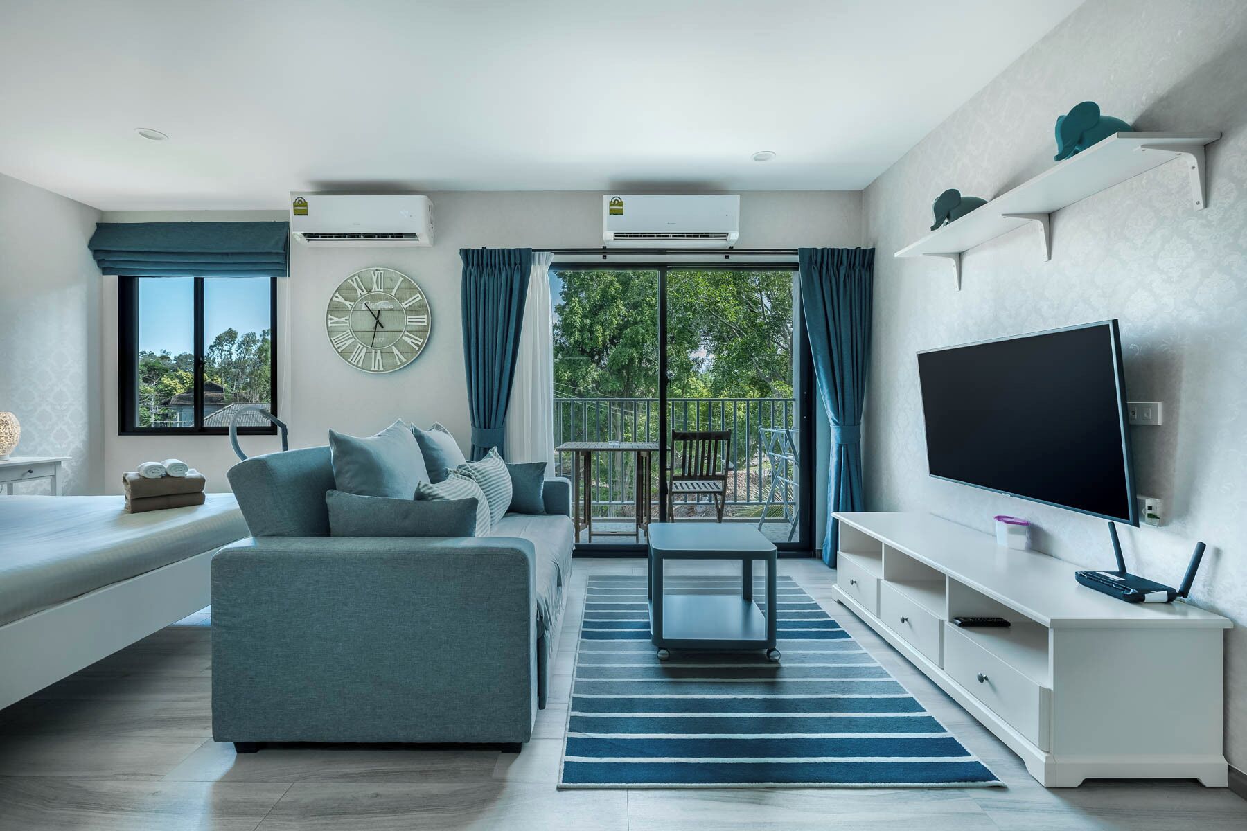 Ein modernes Wohnzimmer mit Sofa, Fernseher und einem Balkon mit Blick.