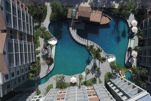 Vista aèria d'un hotel modern amb una piscina central, envoltat de vegetació exuberant i palmeres.