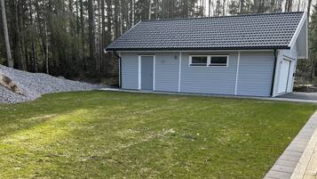 A residential property with a well-maintained lawn, a wooden deck, and a house with a tiled roof.
