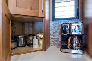 Et kompakt køkken med indbygget kaffemaskine, en brødrister og en kaffekværn.