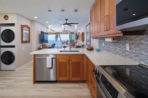 A modern kitchen with wooden cabinets, a stainless steel dishwasher, and a built-in oven. - Beautiful Completely Renovated 2 Bed/2 Bath Oceanfront Gem - Kona Bali Kai #313 (Kailua-Kona)