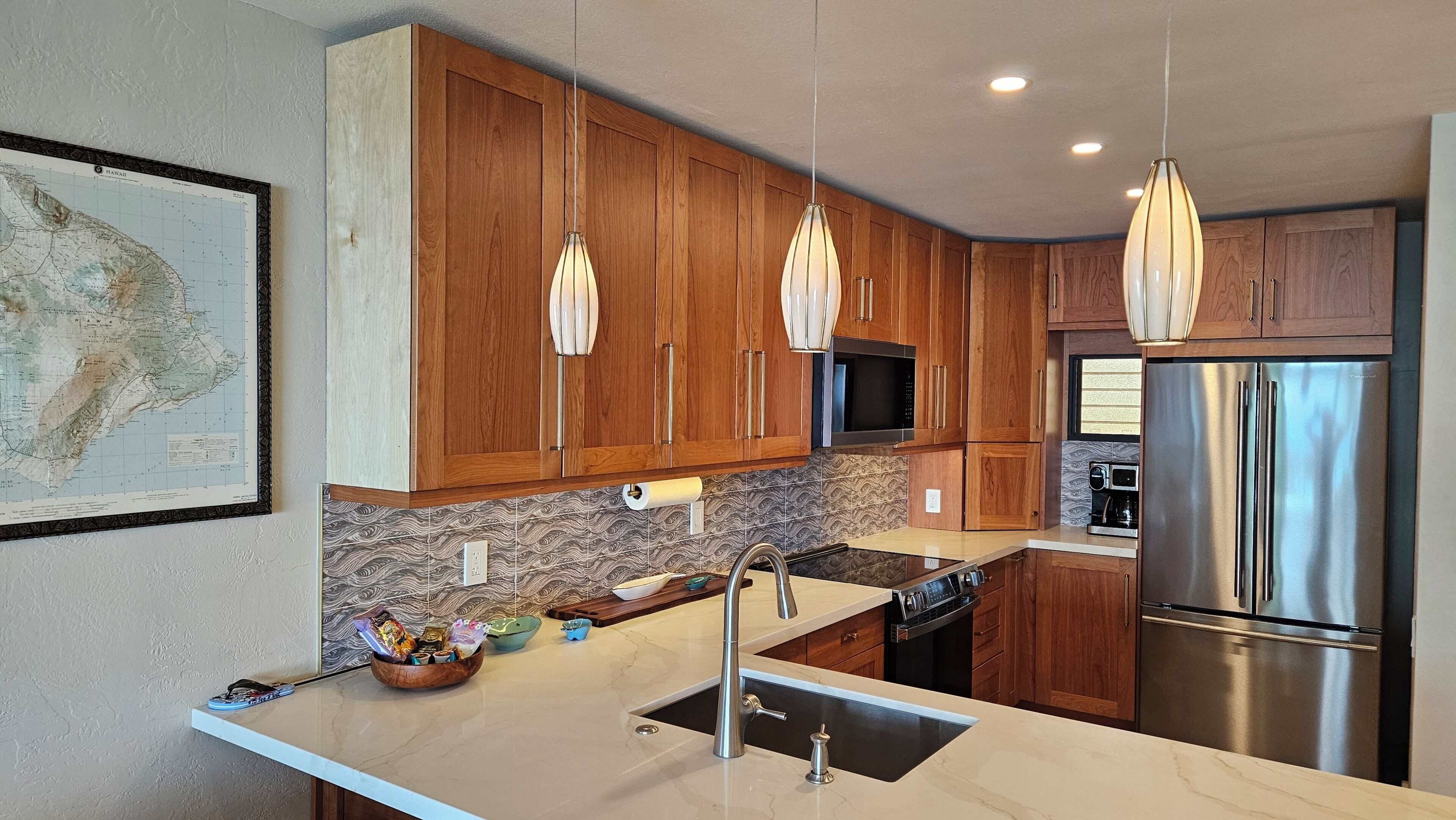 A modern kitchen with wooden cabinets, stainless steel appliances, and pendant lighting.