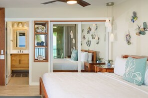 A bedroom with a large bed, a bathroom with a vanity, and a view of the ocean. - Beautiful Completely Renovated 2 Bed/2 Bath Oceanfront Gem - Kona Bali Kai #313 (Kailua-Kona)