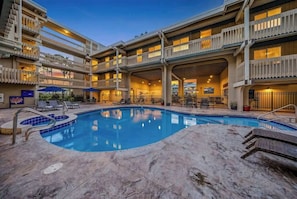 A hotel with a swimming pool, multiple balconies, and outdoor seating areas.