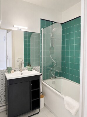 A bathroom with a white sink, black cabinet, and a glass-enclosed shower. - Le Thiers Azur AP4520 by Riviera Holiday Homes (Nice)
