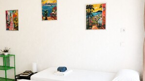 A hotel room with two beds, a green side table, and three paintings on the wall. - Le Thiers Azur AP4520 by Riviera Holiday Homes (Nice)